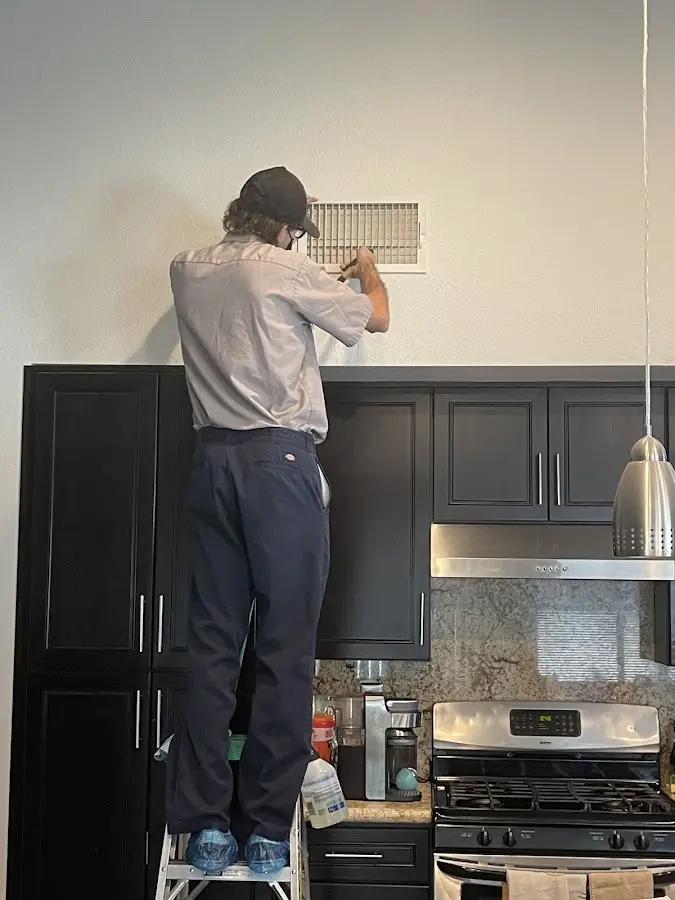 Technician inspecting an air vent during HVAC service in Felida